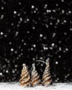 Christmas decorations view of three wooden tree colored in solver glitter at the tips and white hedgehog on dark background with