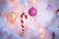 Christmas decorations on a white artificial Christmas tree: a pink balloon and Santa`s candy-striped cane. New year, festive backg Royalty Free Stock Photo