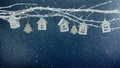Christmas decorations. white tree branch on blue background decorated with glowing toy houses garland Royalty Free Stock Photo