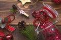 Christmas decorations on a wooden background. Beads in a glass jar with a lid, stars, Santa hat, cones, pine branches. New year, p