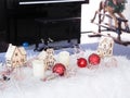 Christmas decorations of wooden houses, balls, candles, lights on white wool, with a piano backdrop. Royalty Free Stock Photo