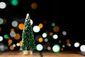 Christmas decorations on a wooden table with glowing lights. A small artificial Christmas tree with light bokeh background Royalty Free Stock Photo