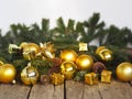 Christmas decorations yellow balls, fir branches on a wooden background with copy space. Gold style. Royalty Free Stock Photo