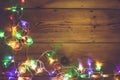 Christmas decorative lights. Christmas garland lights on wood. Colorful Xmas light bulbs on rustic brown plank Royalty Free Stock Photo