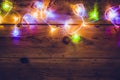 Christmas decorative lights. Christmas garland lights on wood. Colorful Xmas light bulbs on rustic brown plank Royalty Free Stock Photo