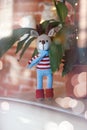 Christmas deer. Closed up toy amigurumi deer in striped sweater and stylish blue scarf stands near flowerpot.