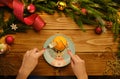 Christmas diet concept. Female eating orange on a Christmas plate. Wooden background with tree branches