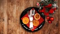 Christmas dinner decoration with dried oranges and a red napkin on a black plate Royalty Free Stock Photo