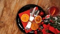 Christmas dinner decoration with dried oranges and a red napkin on a black plate Royalty Free Stock Photo