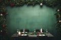 Christmas dinner setting under a garland with candles on a rustic table and green backdrop. Copy space. Christmas greeting card