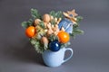 Christmas edible bouquet with nuts, tangerines, nobilis and christmas decor in a blue cup on a gray background