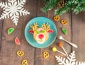 Christmas edible deer of buns and marmalade on a plate on a wooden table next to candy and Christmas tree branches.Christmas kids