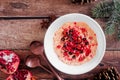 Christmas eggnog oatmeal with crushed candy cane, pomegranates and chocolate chips, table scene over dark wood Royalty Free Stock Photo