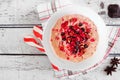 Christmas eggnog oatmeal with crushed candy cane, pomegranates and chocolate chips, table scene over white wood Royalty Free Stock Photo