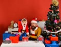 Christmas eve concept. Santa and little assistant among gift boxes Royalty Free Stock Photo