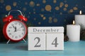 Christmas Eve - December 24. Block calendar, alarm clock and burning candles on light blue wooden table Royalty Free Stock Photo