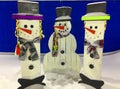 Christmas Eve, Winter day with snowfall. Snowmen made of wood stand in a snowdrift in the evening, on a blue background Royalty Free Stock Photo