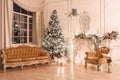 Christmas evening by candlelight. classic apartments with a white fireplace, decorated tree, sofa, large windows and Royalty Free Stock Photo
