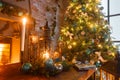 Christmas evening by candlelight. classic apartments with a white fireplace, decorated tree, sofa, large windows and Royalty Free Stock Photo