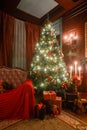 Christmas evening by candlelight. classic apartments with a white fireplace, decorated tree, sofa, large windows and Royalty Free Stock Photo