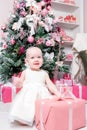 Christmas evening. Little girl sitting and unwraps gifts. white dress Princess Royalty Free Stock Photo