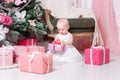 Christmas evening. Little girl sitting and unwraps gifts. white dress Princess Royalty Free Stock Photo