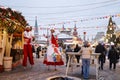 Christmas Fair Gum Fair on Red Square. A man and a woman, actors, in traditional Russian costumes walk and dance on stilts.