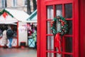 Christmas fair outdoor decoration festive atmosphere urban area with traditional British phone cabin red color foreground and Royalty Free Stock Photo