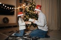 Christmas family celebration. Smiling young man exchanging sharing xmas gifts with his cute daughter Royalty Free Stock Photo