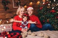 Christmas family with child smiling near the Xmas tree. Living room decorated by Christmas tree and present gift boxes Royalty Free Stock Photo