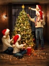 Christmas Family Decorate Xmas tree with Toys. Parents and Kids in Santa Hats together around Fir tree in cozy Living Room Royalty Free Stock Photo