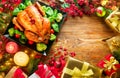 Christmas family dinner. Roasted chicken on holiday table, decorated with gift boxes, burning candles and garlands Royalty Free Stock Photo