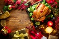 Christmas family dinner. Roasted chicken on holiday table, decorated with gift boxes, burning candles and garlands Royalty Free Stock Photo