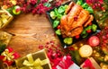 Christmas family dinner. Roasted chicken on holiday table, decorated with gift boxes, burning candles and garlands Royalty Free Stock Photo