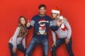 Christmas family! Happy mom,dad and little daughter on Santa Claus hats on red background. Enjoyng love hugs, holidays people. Royalty Free Stock Photo
