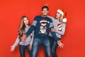 Christmas family! Happy mom,dad and little daughter on Santa Claus hats on red background. Enjoyng love hugs, holidays people. Royalty Free Stock Photo