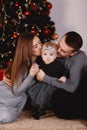 Christmas family kissing and hugging. Child surprised his mother and father with a Christmas gift. Family near christmas tree. Royalty Free Stock Photo