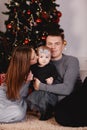 Christmas family kissing and hugging. Child surprised his mother and father with a Christmas gift. Family near christmas tree. Royalty Free Stock Photo