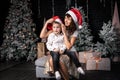 Christmas in the family: Mom and her son sit near the Christmas tree and try on Santas cap.