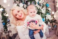 Christmas family, mother and baby smiling near the Xmas tree. Living room decorated by Christmas tree and present gift box Royalty Free Stock Photo