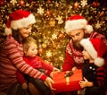 Christmas Family Open Present Gift Box in Home room, Parents with Children in Santa Hats, Decorated Xmas Tree Royalty Free Stock Photo