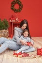 Christmas family. Red Merry Christmas tree background. Woman mother and child daughter celebrate new year. Xmas greeting card. Royalty Free Stock Photo