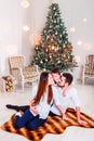 Christmas family smiling and kissing near the Xmas tree. Living room decorated by Christmas tree and present gift box