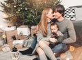 Christmas family smiling and kissing near the Xmas tree. Living room decorated by Christmas tree and present gift boxes Royalty Free Stock Photo