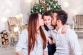 Christmas family smiling and kissing near the Xmas tree. Living room decorated by Christmas tree and present gift box