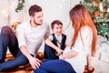 Christmas family smiling and kissing near the Xmas tree. Living room decorated by Christmas tree and present gift box Royalty Free Stock Photo