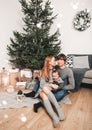 Christmas family smiling and kissing near the Xmas tree. Living room decorated by Christmas tree and present gift boxes, the light Royalty Free Stock Photo