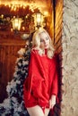 Christmas Fashion woman blonde in the red sweater, having fun and posing against the Christmas tree and lamppost. Winter