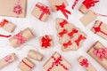 Christmas festive background - different gifts boxes of kraft paper, blank labels and red ribbons, bows on soft white wood board. Royalty Free Stock Photo