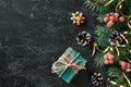 Christmas festive background with gift box, Christmas tree branches and seasonal decorations on black board. Flat lay. Space for Royalty Free Stock Photo